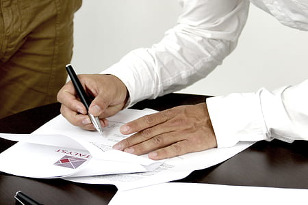 person in white long-sleeved top holding black and silver retractable pen thumbnail