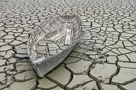grey boat on grey dried and cracked ground at daytime thumbnail