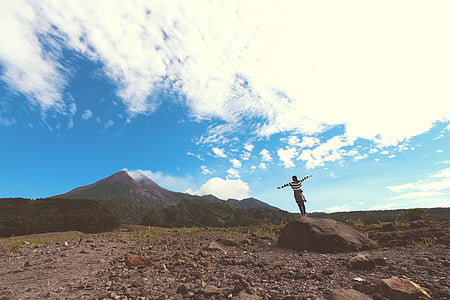woman standing on rock formation near mountain under blue clouds during daytime thumbnail