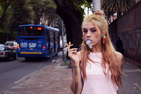 woman smoking on sidewalk near blue bus thumbnail