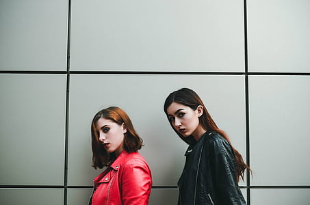 two woman near wall looking on camera thumbnail