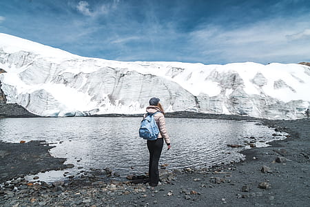 woman in white jacket and black pants standing beside lake thumbnail
