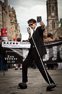 man holding microphone and album wearing sunglasses while standing on concrete ground outside building at daytime thumbnail