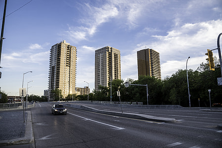 Car on the road with three buildings in the background in Winnipeg thumbnail