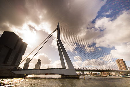 white suspension bridge under sky full of clouds thumbnail