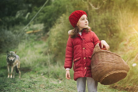 girl walking on green grass pathway holding brown wicker basket thumbnail