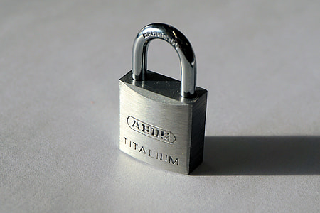 gray Titalium padlock with shadow on gray surface in close-up photography thumbnail