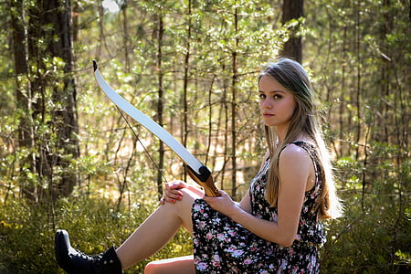 woman in black, red, and pink floral sleeveless dress holding white and brown composite bow thumbnail