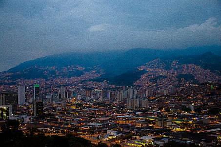aerial view of buildings near mountain under cloudy sky thumbnail