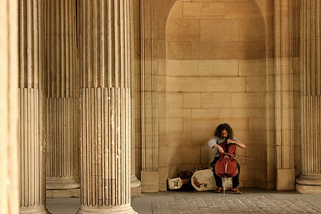 man playing brown viola holding bow sitting on concrete chair thumbnail