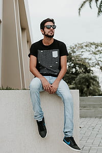 man sitting on gray concrete pavement near green trees thumbnail