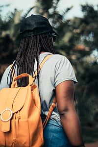 woman wearing leather backpack walking near trees thumbnail