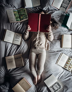 woman reading book while lying on bed thumbnail