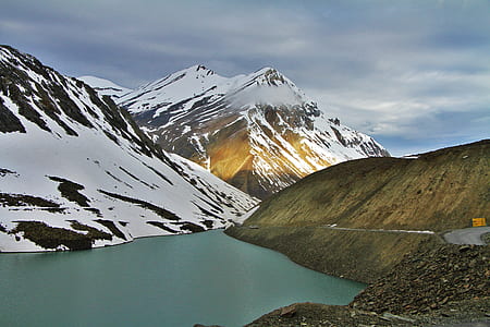 body of water near snow-covered mountain during daytime thumbnail