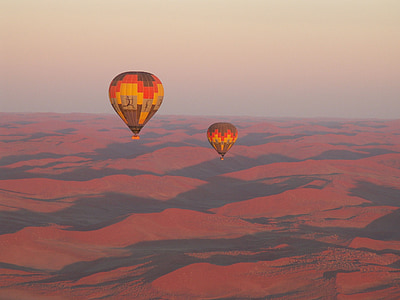 two hot air balloons floating in the sky above desert thumbnail