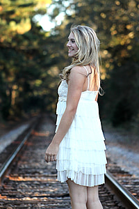 closeup photography of woman standing on train rail wearing white spaghetti strap dress thumbnail