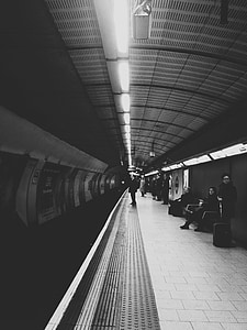 grayscale photograph of person standing on train station thumbnail