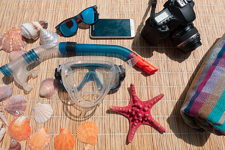 teal and red snorkeling goggles with DSLR camera and sea shells photography during daytime thumbnail