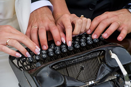 closeup photography of two person holding black typewriter thumbnail