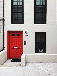 white and black concrete house near road with red door thumbnail