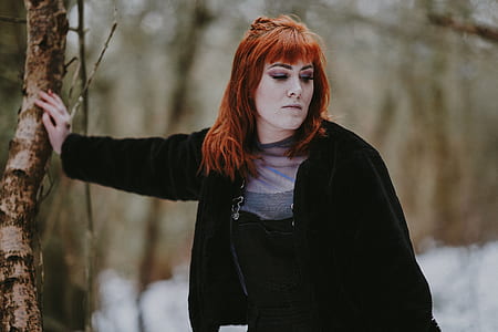 woman wearing black coat standing beside tree at daytime thumbnail