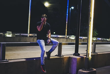 man sitting on edge of bridge railing during dark time thumbnail