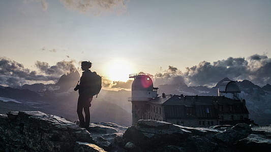 silhouette of person standing on rock formation during daytime thumbnail