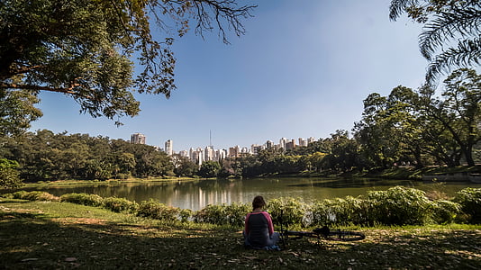 woman sitting on grass looking at lake thumbnail