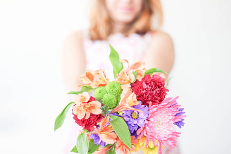 shallow focus photography of woman holding assorted flower bouquet thumbnail