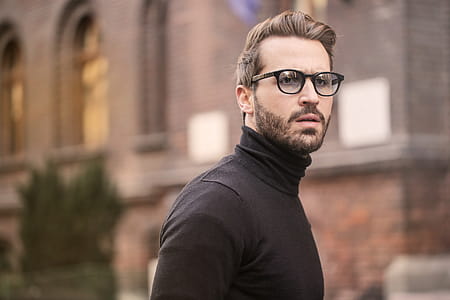 Young bearded male wearing black turtleneck top and eyeglasses posing at the street thumbnail