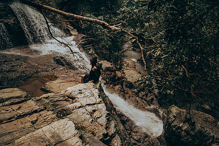 Woman Sitting on Edge Beside Flowing River thumbnail