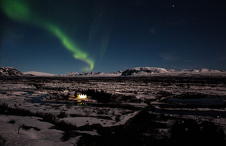aurora on sky during night time above trees and mountains thumbnail