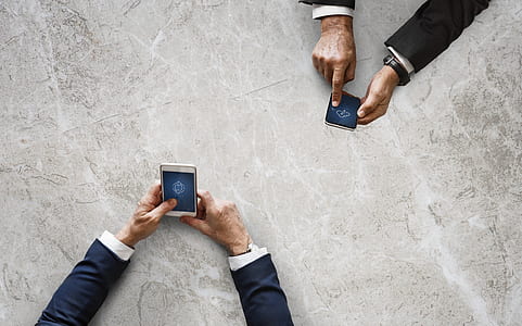 two man wearing suit jackets holding smartphones thumbnail
