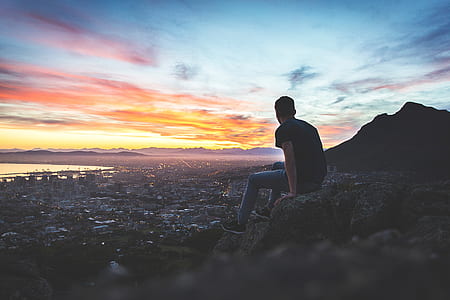 man sitting on hill with cityscape view thumbnail