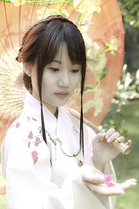woman wearing white kimono holding oil paper umbrella and pink petaled flower thumbnail