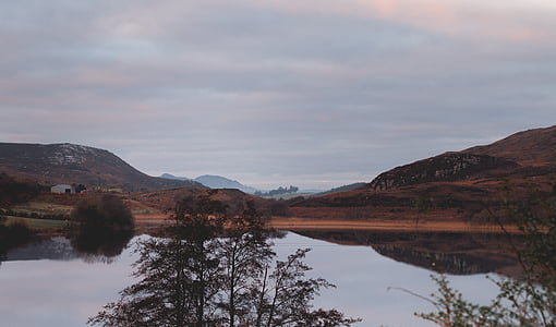 body of water near mountain under cloudy sky thumbnail