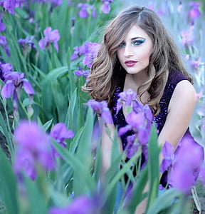 woman wearing purple sleeveless dress surrounded with purple petal flowers thumbnail