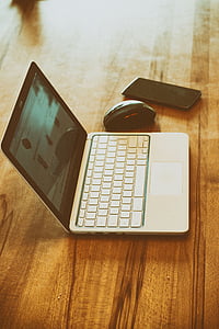 black smartphone beside black and silver laptop computer on brown wooden surface thumbnail