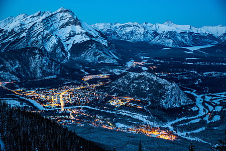 aerial photography of lighted buildings near mountain covered with snow thumbnail