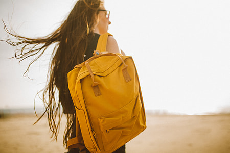 woman wearing black tank top with brown backpack hanged on her right shoulder walking on brown plains photo thumbnail