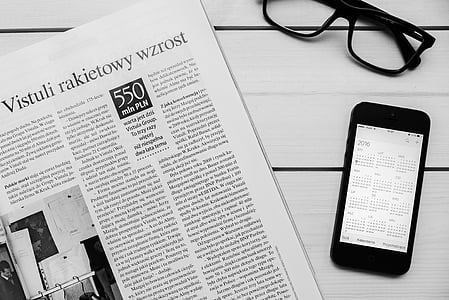 black Android smartphone beside newspaper thumbnail