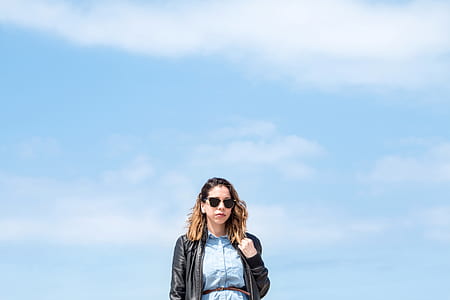 woman wearing black leather jacket holding hair during daytime thumbnail