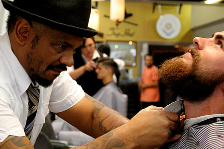 man trimming another man's beard using gray shaver thumbnail