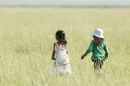two girls walking on grass field during daytime thumbnail