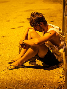 man sitting beside black fence thumbnail