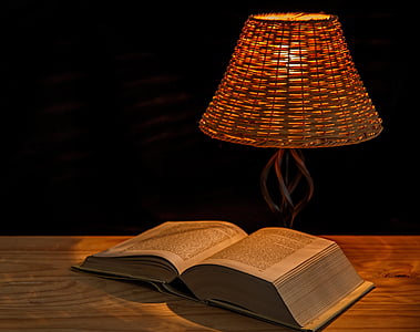 opened book on table near turned on table lamp thumbnail