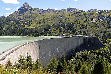 concrete reservoir near trees and mountains at daytime thumbnail