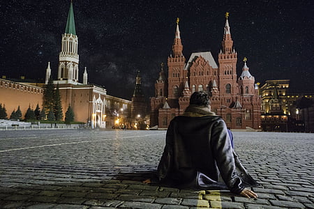 person sitting on street in front of brown brick building thumbnail
