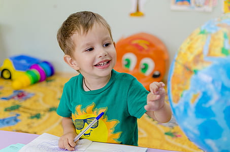 boy wearing green t-shirt pointing at desk globe thumbnail
