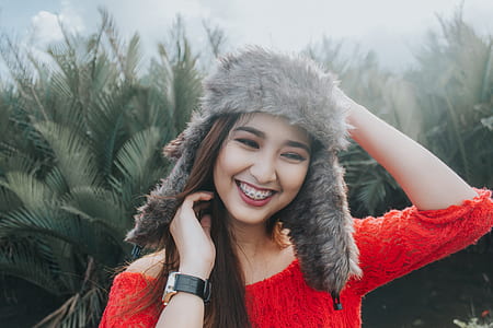 Woman In Red Off Shoulder Top Wearing Fur Beanie Smiling for Photo thumbnail